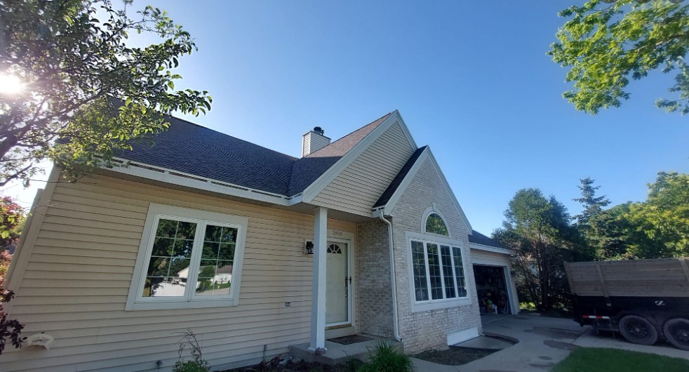 Front view of a yellow single story home with a slanted roof installed by rooster roofing in Beloit WI