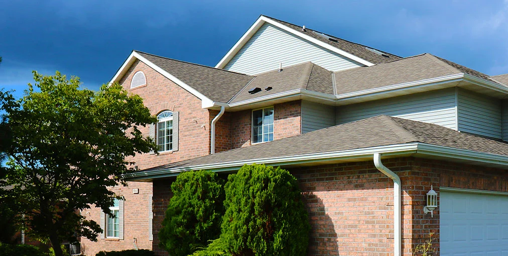 Front view of a 2 story home in Clinton WI with a new roof installed by rooster roofing. Multiple levels, garage and slanted roof.