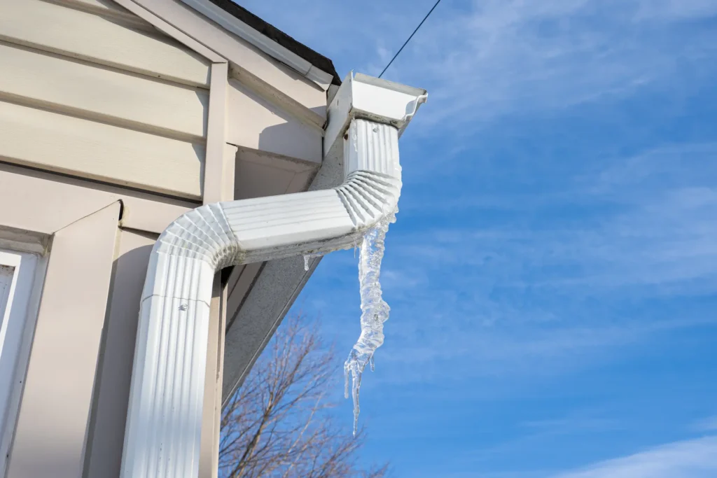 Icicle hanging from gutter downspout after crack causes leak